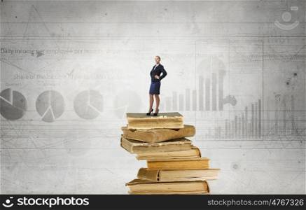 She reached the top. Confident businesswoman standing on pile of books