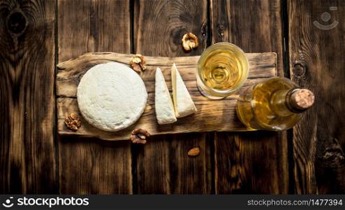 Sheep cheese with white wine and walnuts. On a wooden table.. Sheep cheese with white wine and walnuts.