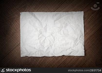 sheet of crumpled paper on dark rusty brown wooden background