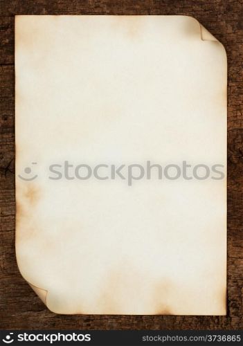 Sheet of old paper with curled edges on the wooden background