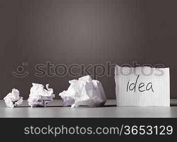 sheet of paper with word idea and crumpled wads on table.