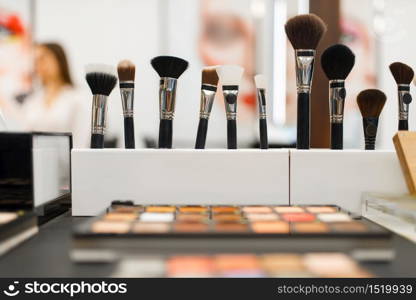 Shelf with shadows and brushes in cosmetics store, nobody. Luxury beauty shop, showcase with products in fashion market. Shelf with shadows and brushes in cosmetics store