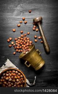 Shelled hazelnuts in an old mortar and pestle. On the black wooden table.. Shelled hazelnuts in an old mortar and pestle.