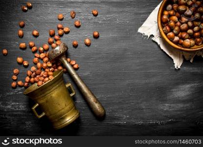 Shelled hazelnuts in an old mortar and pestle. On the black wooden table.. Shelled hazelnuts in an old mortar and pestle.