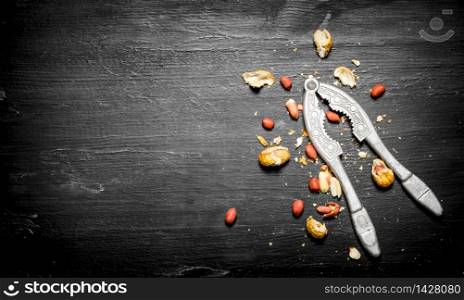 Shelled peanuts with the shell and a Nutcracker. On the black wooden table. Shelled peanuts with the shell and a Nutcracker.