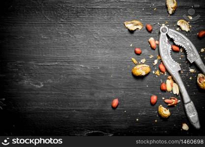 Shelled peanuts with the shell and a Nutcracker. On the black wooden table. Shelled peanuts with the shell and a Nutcracker.