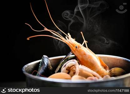 Shellfish seafood plate with shrimps prawns mussel squid ocean gourmet dinner seafood cooked boiled in hot pot with herbs and spices on dark background
