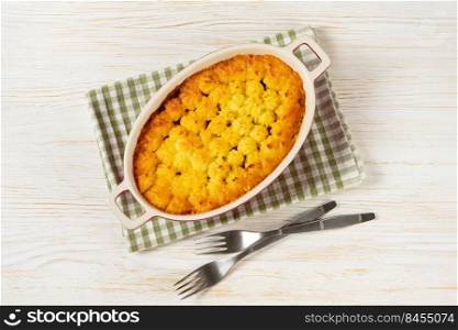 Shepherd’sπe or Cotta≥πe. Minced meat, mashed potatoes and ve≥tab≤s cassero≤on white wooden background. Traditonal British, United Kingdom, Ireland cuisi≠. Top view, flat lay. Shepherd’s Pie or Cotta≥Pie, traditional British dish on white wooden background