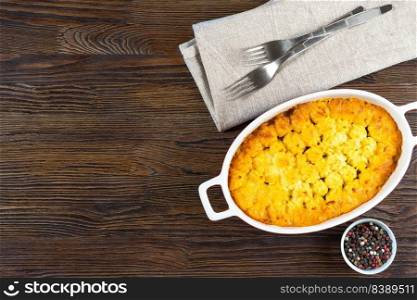 Shepherd’s pie or Cottage pie. Minced meat, mashed potatoes and vegetables casserole on brown wooden background. Traditonal British, United Kingdom, Ireland cuisine. Top view, flat lay with copy space. Shepherd’s Pie or Cottage Pie, traditional British dish on brown wooden backgfound