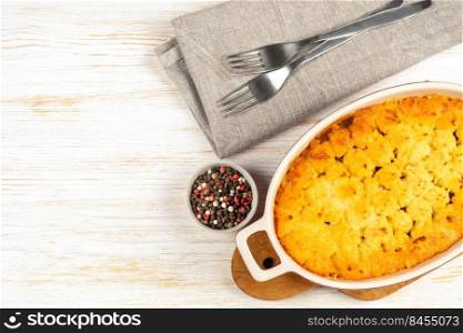 Shepherd’s pie or Cottage pie. Minced meat, mashed potatoes and vegetables casserole on white wooden background. Traditonal British, United Kingdom, Ireland cuisine. Top view, flat lay with copy space. Shepherd’s Pie or Cottage Pie, traditional British dish on white wooden background