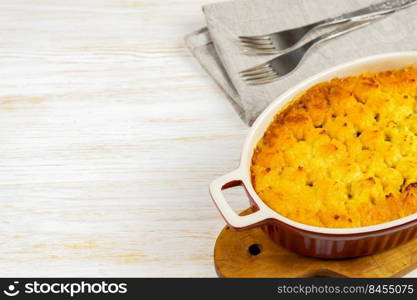 Shepherd’s pie or Cottage pie. Minced meat, mashed potatoes and vegetables casserole on white wooden background with copy space for text. Traditonal British, United Kingdom, Ireland cuisine. Shepherd’s Pie or Cottage Pie, traditional British dish on white wooden background
