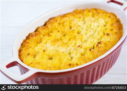 Shepherd’s pie or Cottage pie. Minced meat, mashed potatoes and vegetables casserole on white wooden background. Traditonal British, United Kingdom, Ireland cuisine. Close up view. Shepherd’s Pie or Cottage Pie, traditional British dish on white wooden background
