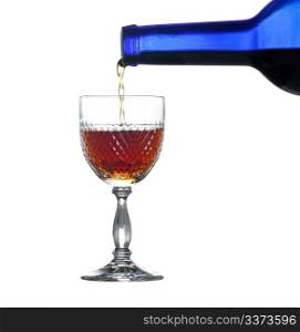 Sherry, port or whisky being poured from blue wine bottle into an elegant cut glass and isolated against white