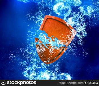 Shield under water. Shield sinking and dissolving in clear blue water