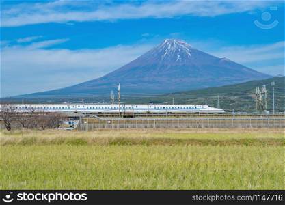Shinkansen train. Fast bullet train, driving and passing Mountain Fuji near Tokyo railway station with with green rice field, Japan