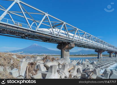 Shinkansen train. Fast bullet train, driving and passing Mountain Fuji near Tokyo railway station with steel bridge over Fuji river, Shizuoka, Japan