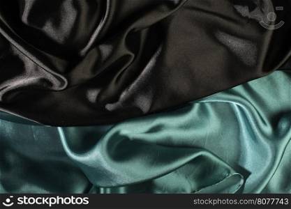 Shiny black and green satin pleated fabric background. Close up