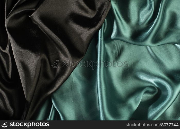 Shiny black and green satin pleated fabric background. Close up