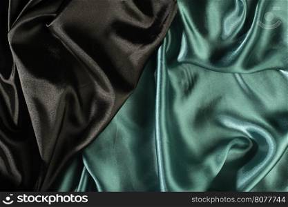 Shiny black and green satin pleated fabric background. Close up