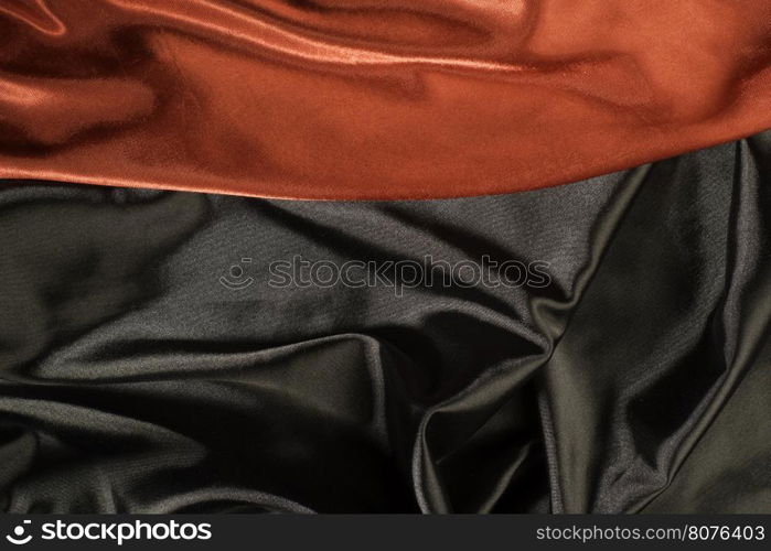 Shiny black and red satin pleated fabric background. Close up