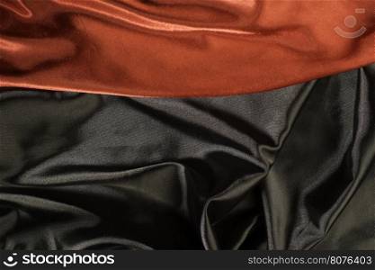 Shiny black and red satin pleated fabric background. Close up