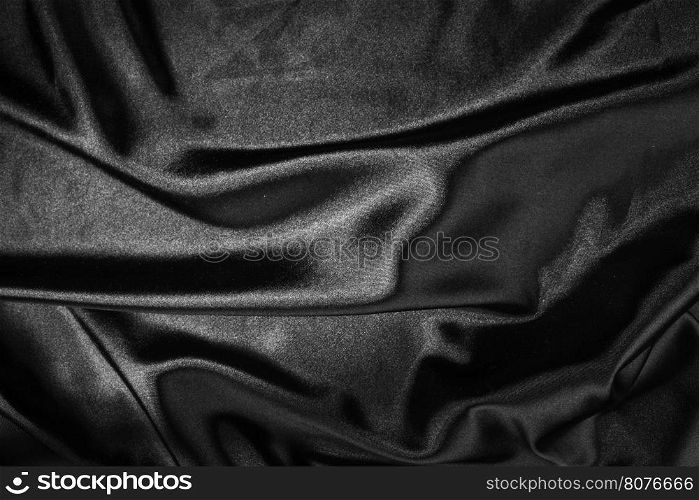 Shiny black satin pleated fabric background. Close up