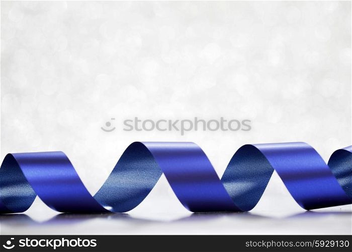 Shiny blue gift ribbon on bokeh background close-up