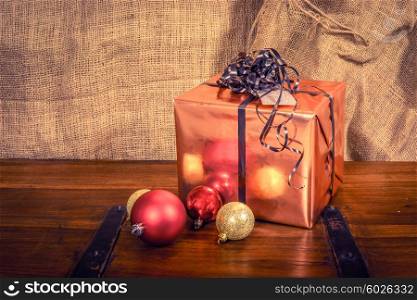 Shiny Christmas gift on a wooden table with baubles