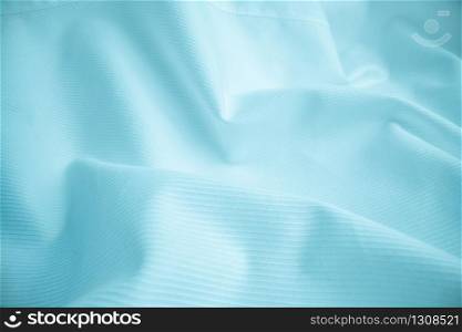 Shiny flowing cloth texture in macro shot. Wavy clean silk weave material. Textile abstract background.