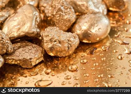 shiny gold nuggets and water drop background. closeup.