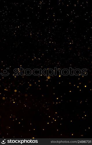 Shiny golden glitter dust particles falling on black background