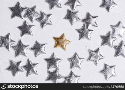 Shiny golden star in center of silver stars on white textured background