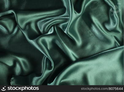Shiny green satin pleated fabric background. Close up