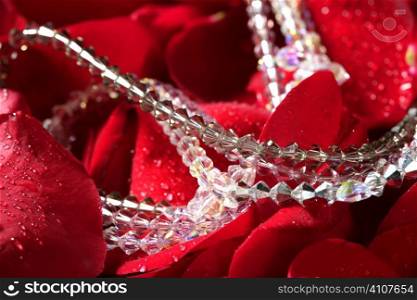 Shiny jewelry over bed or red rose petals