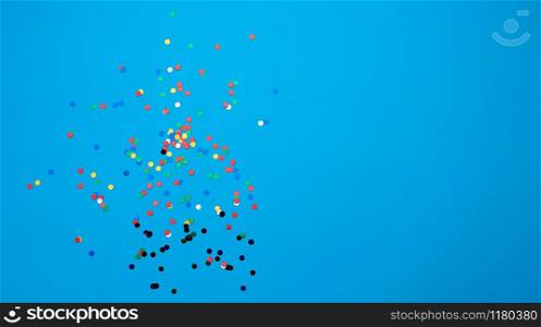 shiny multicolored round confetti scattered on a blue background, festive backdrop for birthday, valentines day. Festive decoration element. Flat design, copy space