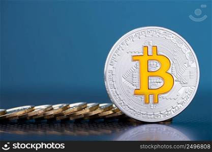 Shiny silver bitcoin with bit logo symbol and coins on dark blue background