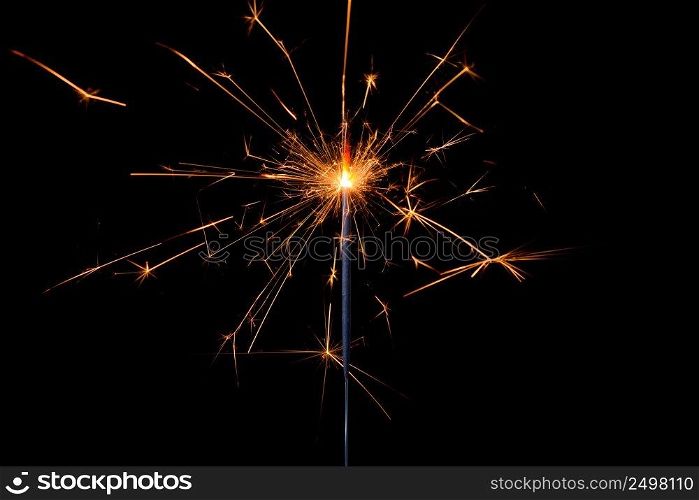 Shiny sparkler with lots of sparks burning bright isolated on black background.