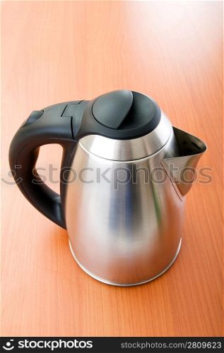 Shiny tea kettle on the wooden table