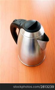 Shiny tea kettle on the wooden table