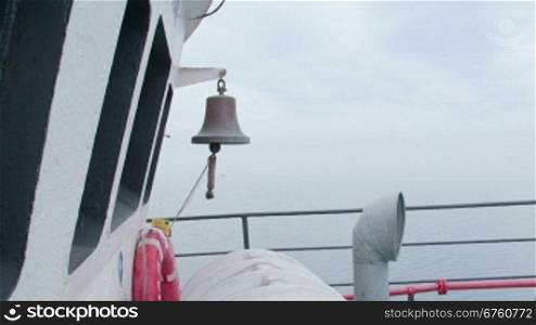 Ship bell on deck of commercial fishing boat in the misty sea