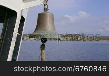 Ship bell on deck of commercial fishing boat moving along the shore