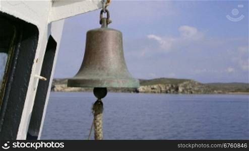 Ship bell on deck of commercial fishing boat moving along the shore
