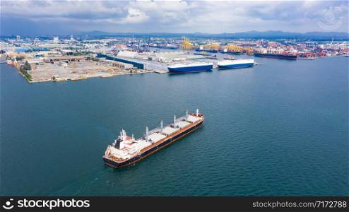 shipping logistics business by the sea and terminal storage container ship with industrial city background aerial view from drone camera at rayong Thailand