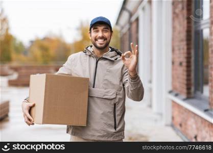 shipping, transportation and people concept - happy smiling delivery man with parcel box showing ok gesture. smiling delivery man with parcel box showing ok