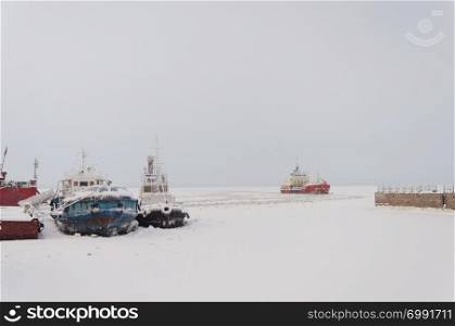 Ships at the pier among the ice on the Northern Dvina river in Arkhangelsk, North Russia. Winter frosty day.