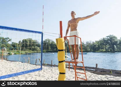 shirtless man acting as referee beach volleyball match