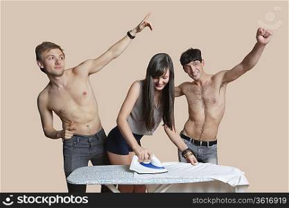 Shirtless men with woman ironing shirt over colored background