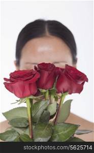 Shirtless woman behind a bunch of beautiful red roses, obscured face, studio shot