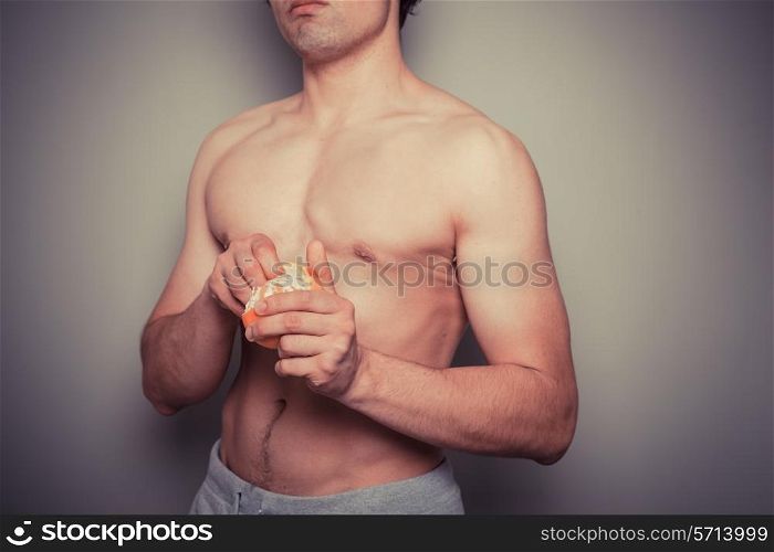 Shirtless young man peeling an orange