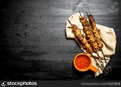 Shish kebab and tomato paste on the old fabric. On the black wooden table.. Shish kebab and tomato paste on the old fabric.